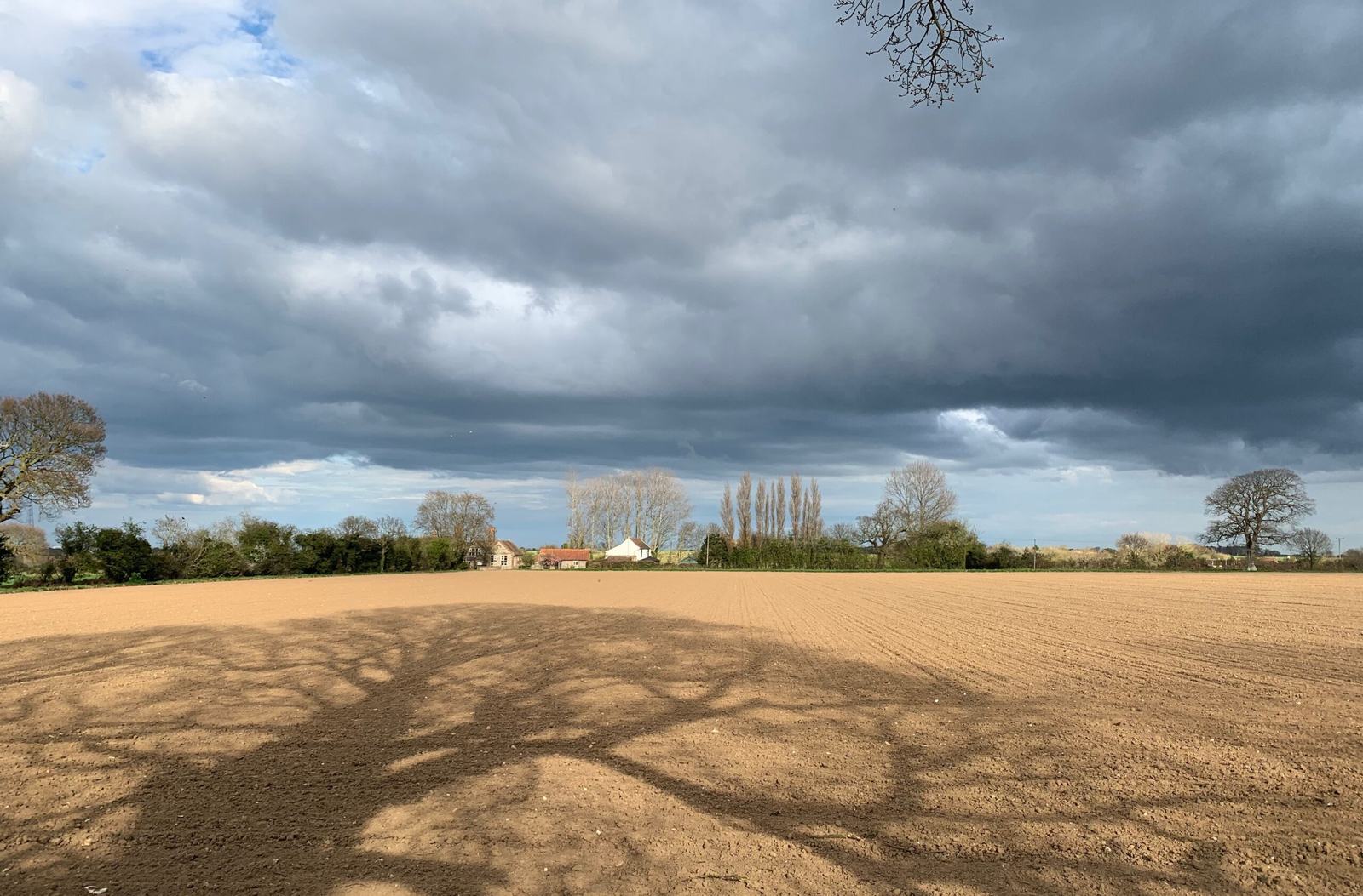 A ploughed field under heavy grey clouds on the farm in North Norfolk where Philosophers Barn Mastering is based