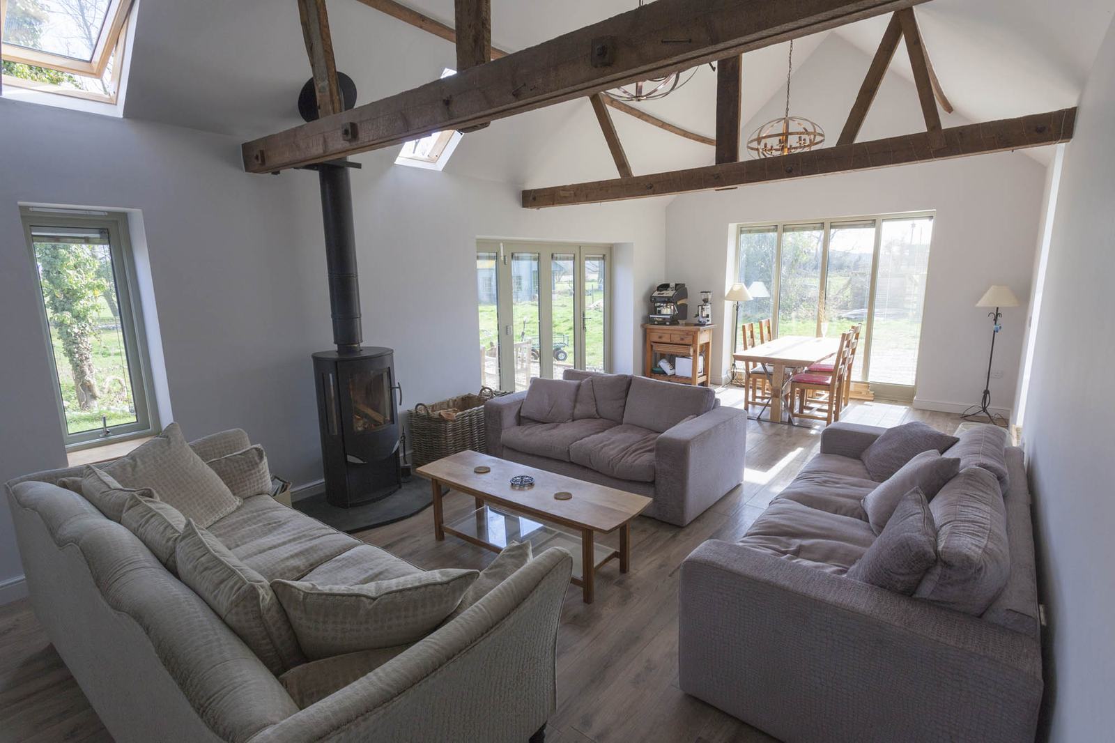 The client lounge in the second converted barn, with a wood burner, sofas and a view through the windows